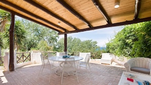An outdoor patio with a round table and chairs, surrounded by greenery and a wooden pergola. - 3 bedroom amazing home in Parghelia -VV- (Parghelia -VV-)