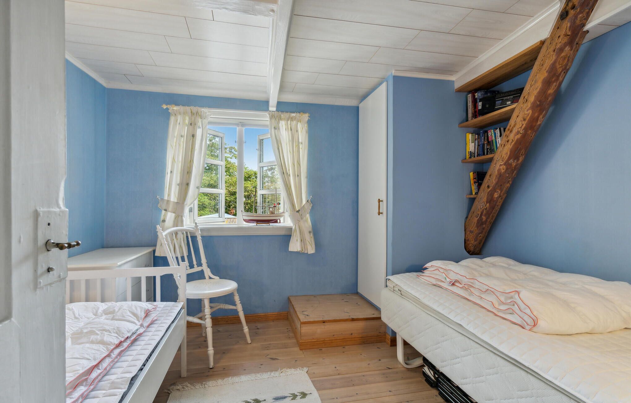 Un dormitorio con cama, escritorio, silla y ventana con cortinas.