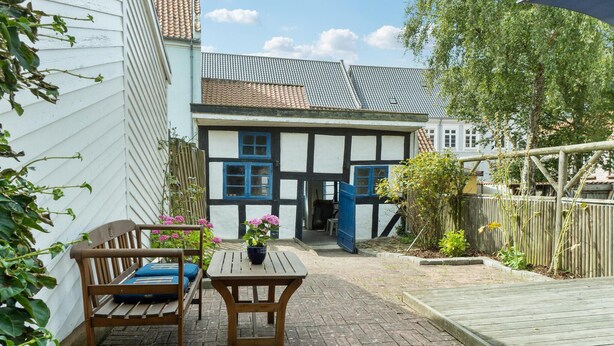 Una casa tradizionale a graticcio con panchina e tavolo in legno, un giardino con piante e un patio in legno.