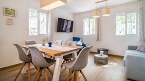 Una sala moderna con una mesa de comedor de madera, sillas tapizadas en gris, un sofá azul y una mesita redonda.