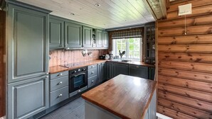 Una cocina con armarios grises, encimera de madera y ventana con vista a zonas verdes.