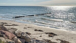 En strand med en klippefyldt kystlinje og en bølgebryder, der strækker sig ud i havet.