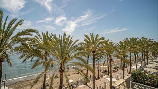 A beachside resort with palm trees, a pool area, and a view of the sea. - Stunning home in Marbella with WiFi (Marbella)