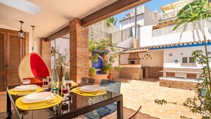A dining area with a glass table, yellow placemats, and a red hanging chair. - Stunning home in Marbella with WiFi (Marbella)