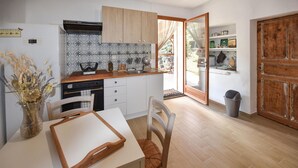 Eine kompakte Küche mit Holzausziehtisch, weißen Schränken und einem Essbereich mit weißem Tisch und Stühlen.