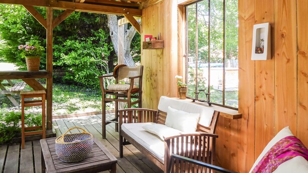 Eine Holzterrasse mit einer Couch, Stühlen und einem Tisch.