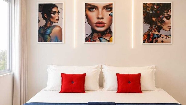 A bedroom with a bed, red and white pillows, a blue bedspread, and three framed artworks on the wall. - Casa hotel Piracicaba  (Piracicaba)