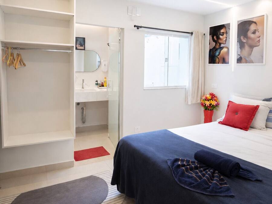 Una habitación de hotel moderna con cama, vestidor, baño y ventana.