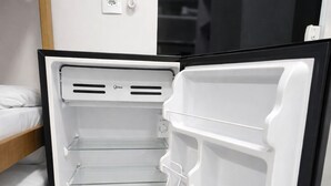 A modern kitchen with a built-in refrigerator, a wooden shelf unit, and a white wall-mounted phone. - Casa hotel Piracicaba  (Piracicaba)