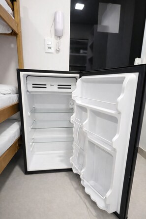A modern kitchen with a built-in refrigerator, a wooden shelf unit, and a white wall-mounted phone. - Casa hotel Piracicaba (Piracicaba)