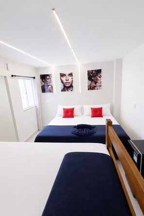 A hotel room with two beds, a wooden headboard, a window with a curtain, and wall-mounted artwork.
