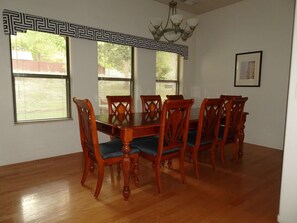A dining room with a wooden table and chairs, large windows with blinds, a chandelier, and a framed picture on the wall. - Spacious and modern comforts on a southwest ranch (Cornville)
