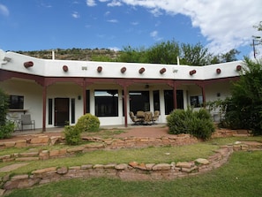 A building with a covered patio, stone landscaping, and a view of a hilly landscape. - Spacious and modern comforts on a southwest ranch (Cornville)