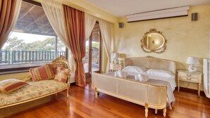 Quarto com cama, sofá, espelho e janela com cortinas.