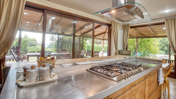 Uma cozinha moderna com uma ilha grande, eletrodomésticos de aço inoxidável e vista para o exterior.