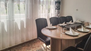 Une salle de conférence dotée d’une table ronde, de fauteuils en cuir noir et offrant une vue sur la verdure à travers de fins rideaux.