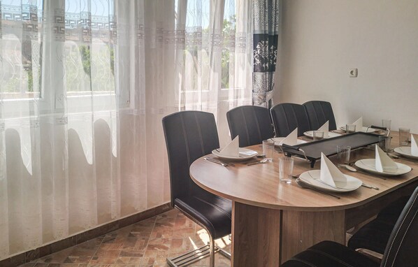 Un salón de conferencias con una mesa redonda, sillas de cuero negro y vistas a zonas verdes a través de cortinas translúcidas.