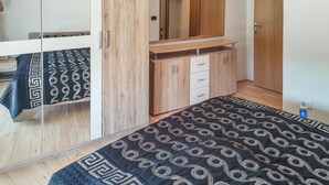 Une chambre à coucher avec un lit, une armoire, un miroir et une petite table.