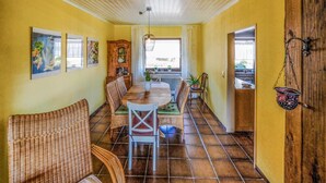 A dining area with wicker chairs, a wooden table, and a cabinet with glass doors.