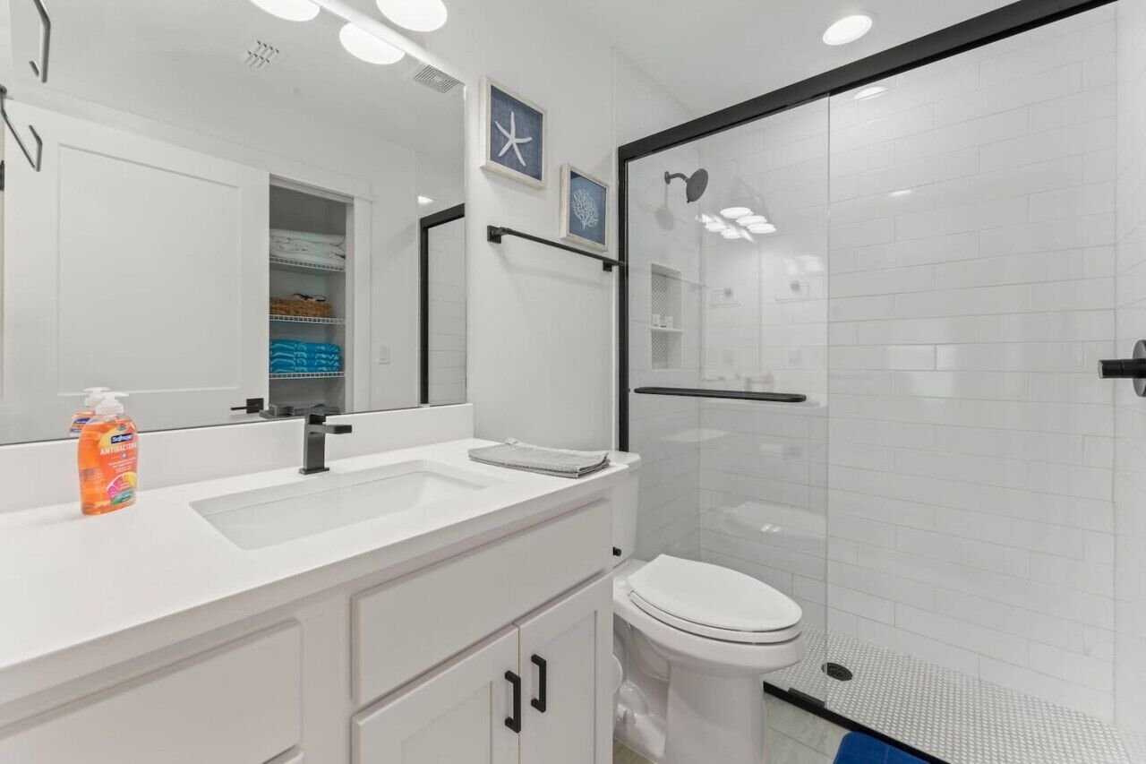 A modern bathroom with a white sink, a toilet, and a glass-enclosed shower area.