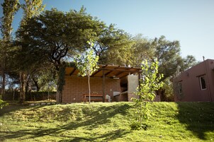 Un edificio de ladrillo con un patio cubierto, un banco y una pequeña mesa.