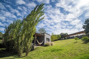 Una casa moderna con una hamaca, un garaje cubierto y un patio con césped.