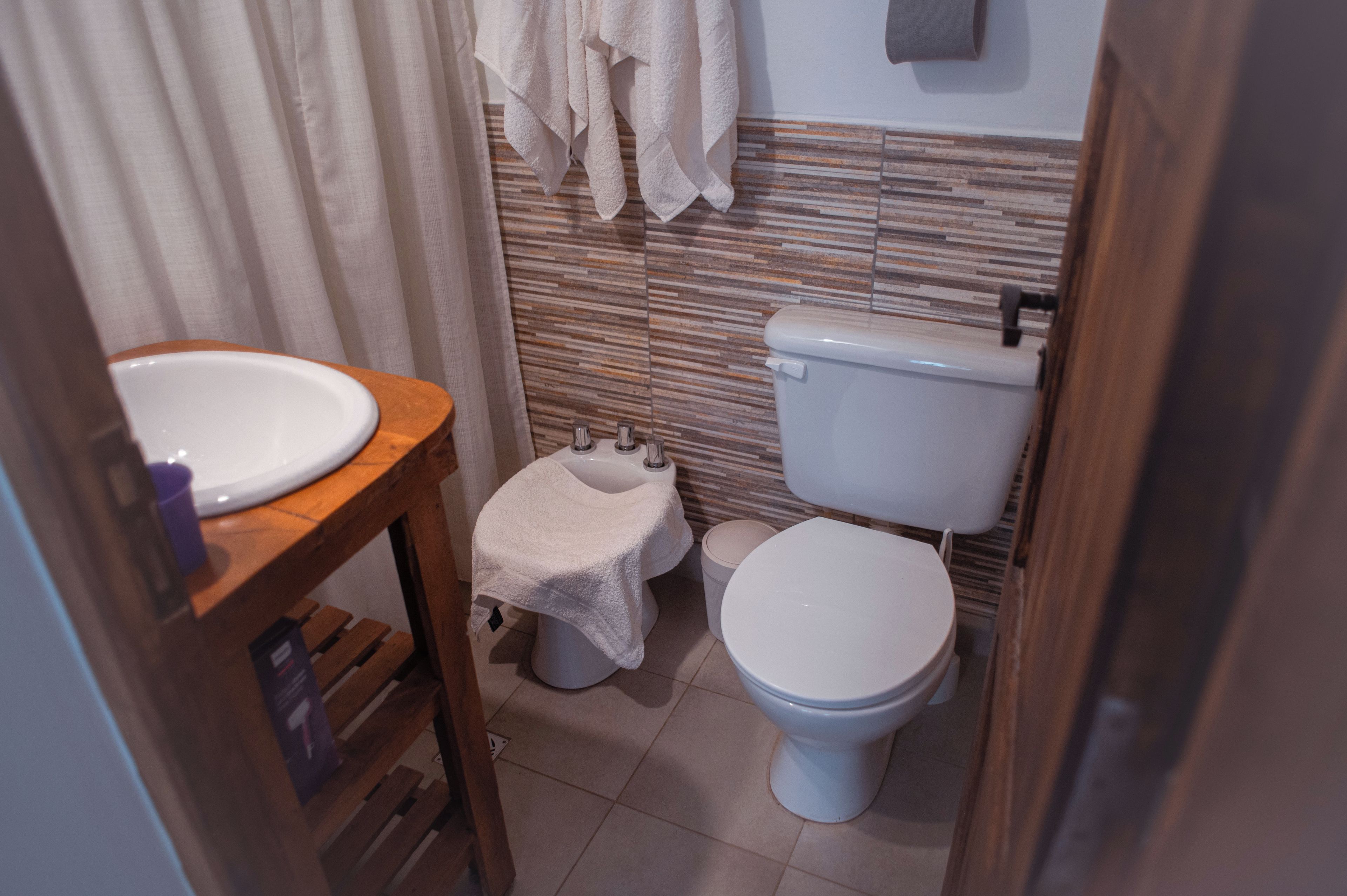 Un baño con tocador de madera, inodoro y lavamanos.