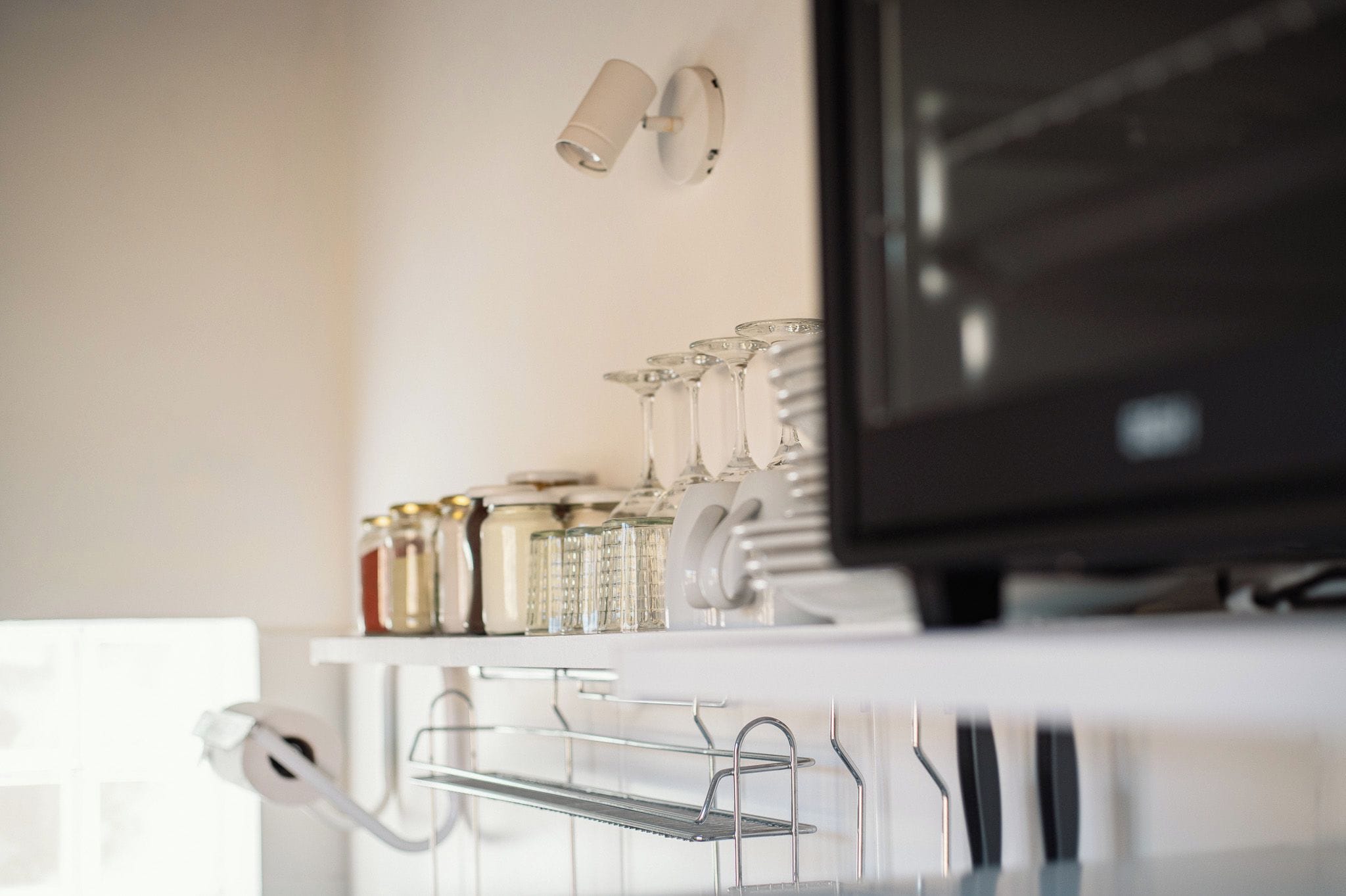 Una encimera de cocina con frascos, vasos y un televisor.