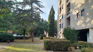 Un cortile con un vialetto, siepi curate e un edificio a più piani con balconi.