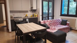Una cucina funzionale con tavolo e sedie, un divano e un'ampia finestra vista verde.