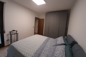 Een slaapkamer met een bed, een kledingkast en een deur naar een andere kamer.