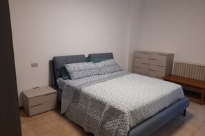 Ein Schlafzimmer mit Bett, Nachttisch, Kommode und Bank.