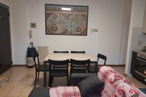 Een zithoek met een tafel, stoelen, een bank, een radiator en een aan de muur bevestigde kaart.