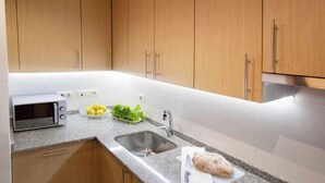 A kitchen with wooden cabinets, a microwave, a sink, and a cutting board with food. - Apartment 5 minutes from the historic center of Pontevedra (Pontevedra)