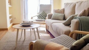 A living room with a beige sofa, a round coffee table, and a chair with a green cushion. - Apartment 5 minutes from the historic center of Pontevedra (Pontevedra)