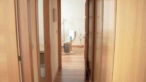 A narrow hallway with wooden doors leading to a room with a bed and a chair. - Apartment 5 minutes from the historic center of Pontevedra (Pontevedra)