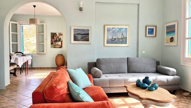 En stue med sofa, sofabord og spiseplads med bord og stole.
