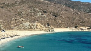 En strand med krystalklart turkis vand, en klippefyldt skråning og en lille båd forankret tæt på kysten.
