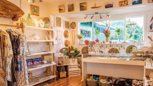 Una tienda boutique con estanterías de madera, artículos colgantes y una vitrina con joyería.