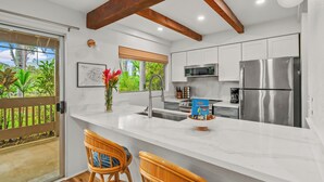 Una cocina moderna con armarios blancos, electrodomésticos de acero inoxidable y una isla grande con taburetes de bar.