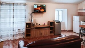 A compact living space with a TV, kitchenette, and a leather sofa. - Nice home in Koromacno (Koromacno)