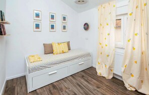 A small, neatly arranged bedroom with a single bed, a shelf with books, and a wall with framed pictures. - Pet friendly apartment in Benkovac (Benkovac)