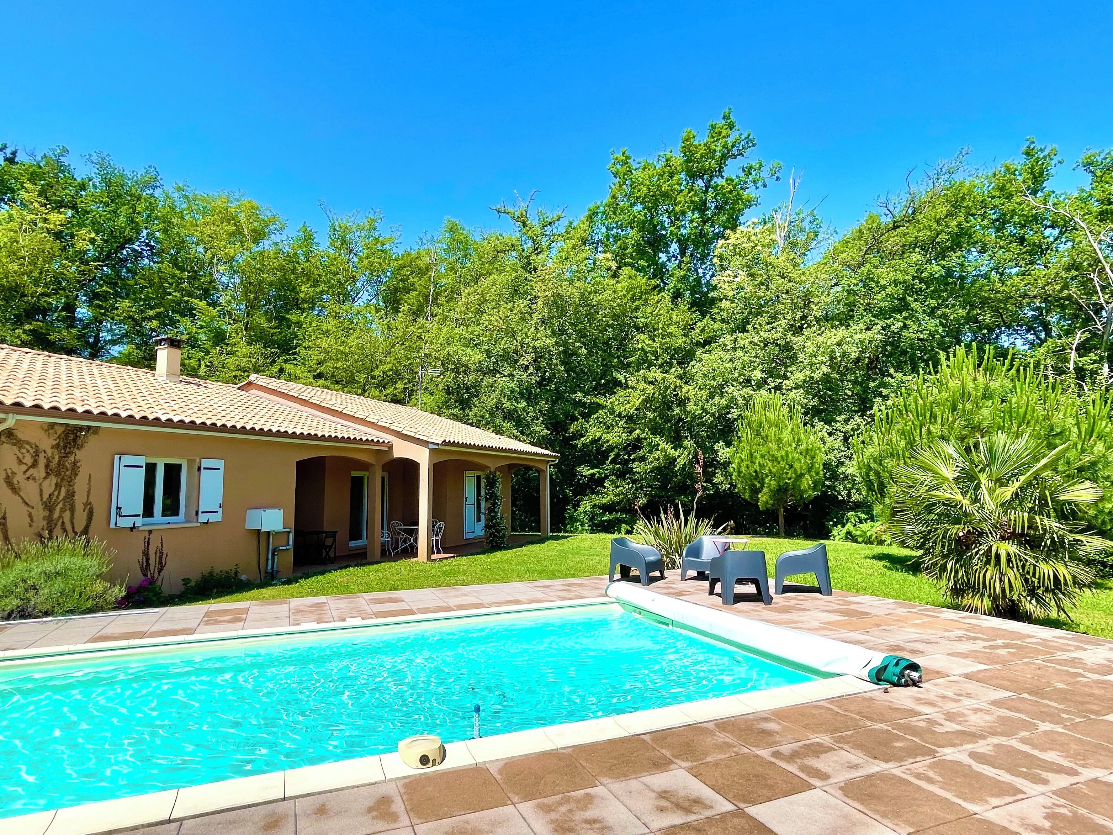 Une maison avec une piscine, du mobilier d’extérieur et une végétation luxuriante.