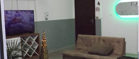 Una sala de estar con televisor, árbol de Navidad y sofá.