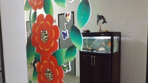 A room with a fish tank, a dark wooden cabinet, and a wall decorated with large floral patterns.