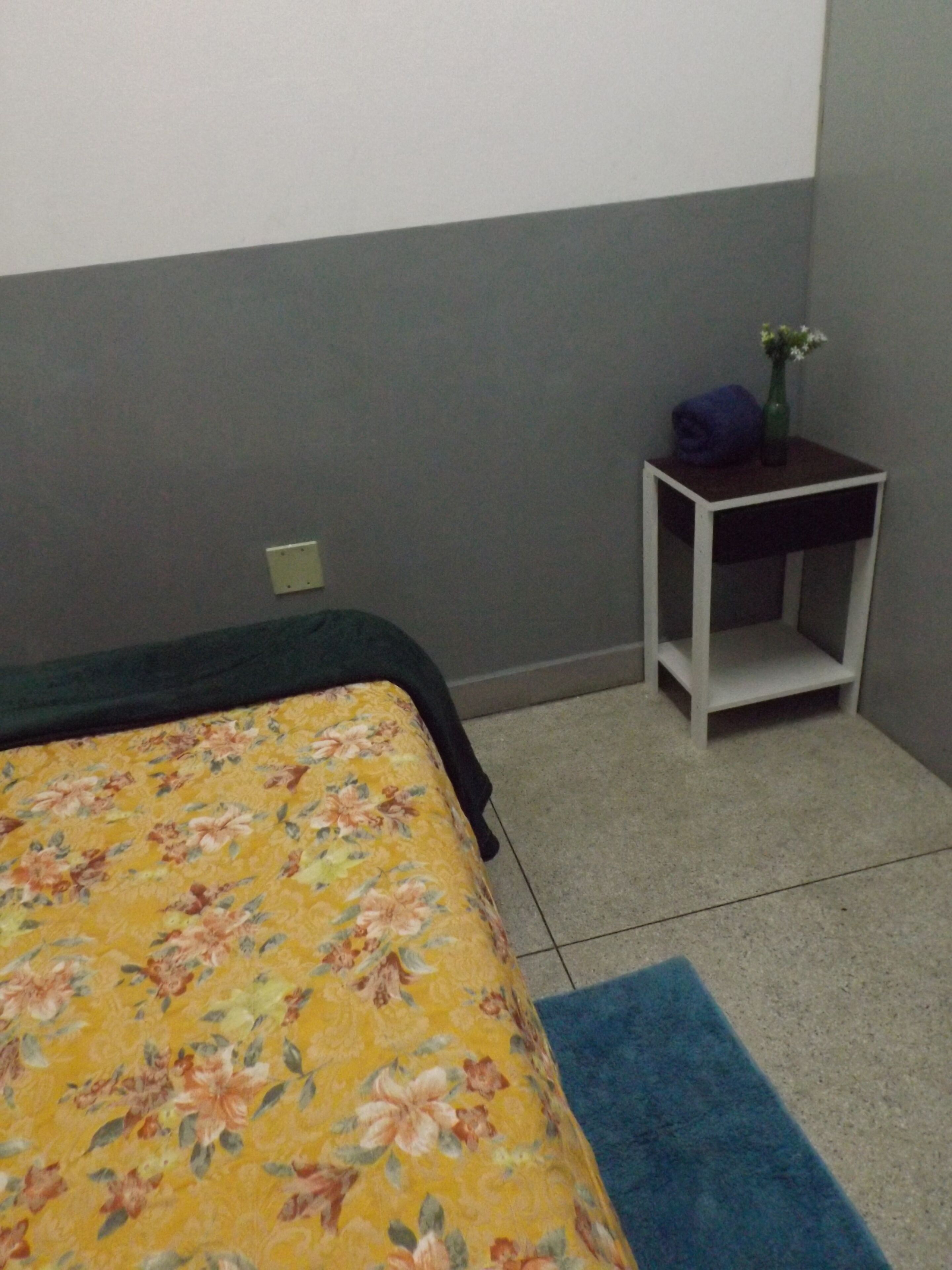 Une pièce comprenant un lit, une petite table de chevet et un tapis.