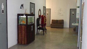 A hallway with a fish tank, a chair, a couch, and numbered doors.