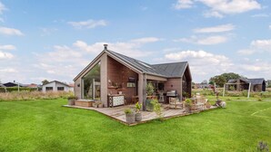 Une maison moderne dotée d’une grande terrasse, d’un espace barbecue et d’un vaste coin salon extérieur.