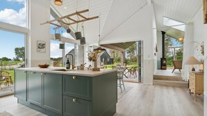 Une cuisine spacieuse dotée d’un grand îlot central, de meubles en bois et de luminaires suspendus.