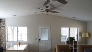 Ein Wohnzimmer mit Essbereich, Deckenventilator, Tür und Bücherregal.
